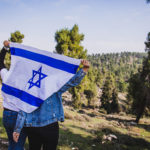 Birthright Israel participants holding an Israeli flag