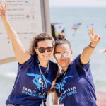 Two Birthright Israel staff members giving the peace sign on a beach in Tel Aviv
