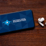 White Apple air pods next to a mobile phone with Birthright Israel Foundation's videos