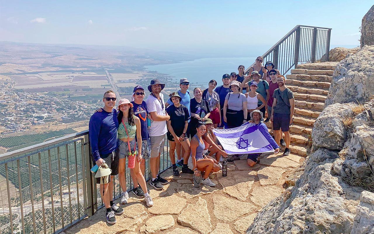 Zander Schnitzer with his Birthright Israel group holding an Israeli flag alongside a scenic view in the Golan Heights