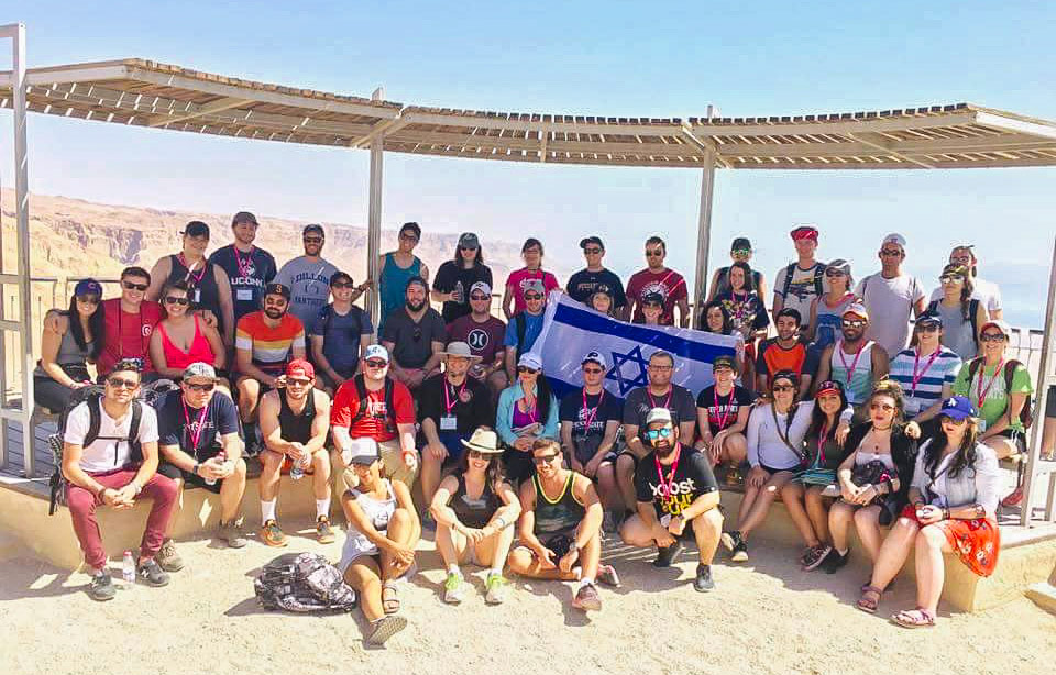 Lior Navon with her Birthright Israel group holding an Israeli flag on top of Masada